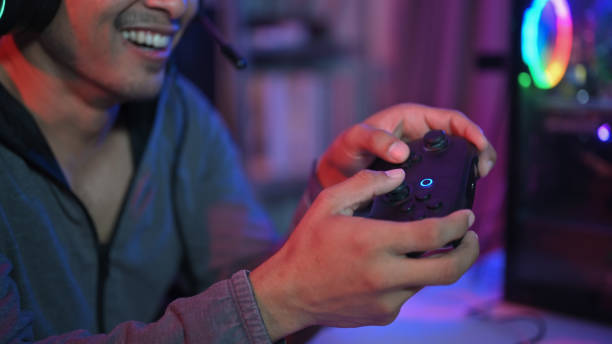 istock Smiling young man holding controller playing video game in gaming room with neon light 1929321783