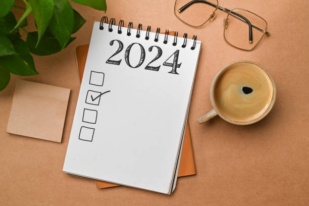 istock 2024 goals list with notebook, coffee cup, plant and glasses on brown background. Plan, journal, to-do list 1929323880