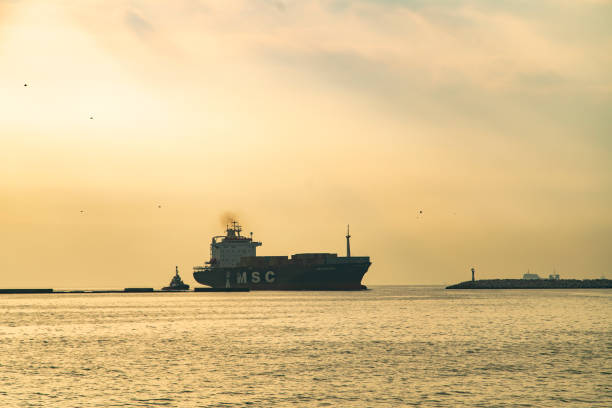 Icel / Turkey - 22 December 2019: Aerial view of cargo container ship approaching port.  Global business logistics import export background and container ship, forklift truck lifting cargo container in shipping yard transport concept.