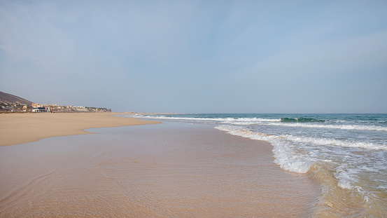 Sea, blue sky and horizon - photo of foaming ocean waves and blue sky with clouds. Blue open sea. Horizon over water. The horizon line. Sea waves against the sky. Blue sky with clouds. White clouds and white waves. Clear water and blue sky. Ocean shore, waves and shore. Seascape.