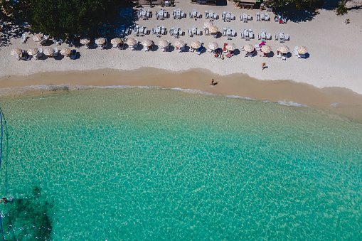 Koh Samet Island Thailand, aerial drone view from above at the Samed Island in Thailand with a turqouse colored ocean and a white tropical beach with beach chairs and umbrellas