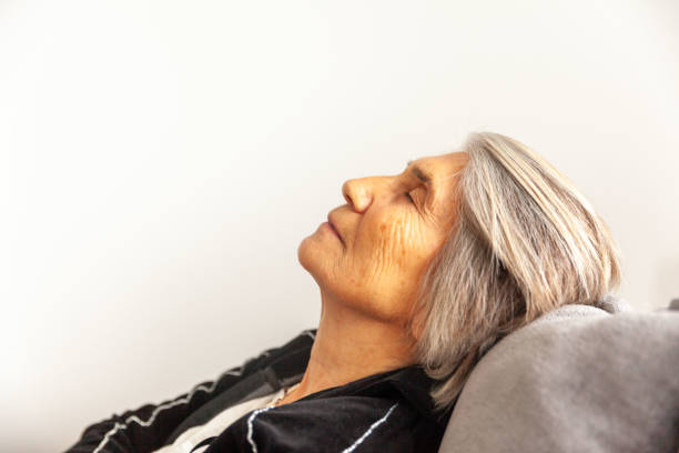 Old wrinkled lady falling asleep in bed