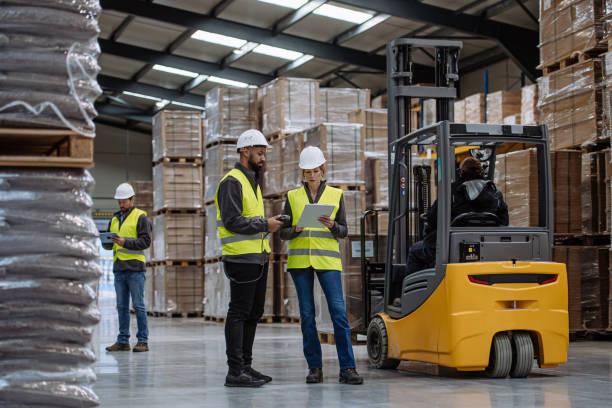 istock Warehouse workers reading product order, order picking. Warehouse manager checking delivery, stock in warehouse, inspecting products for shipment. 1929421670