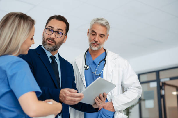 istock Pharmaceutical sales representative talking with doctors in medical building, presenting them new product on tablet, business talk. Hospital director consulting with healthcare staff. 1929423737