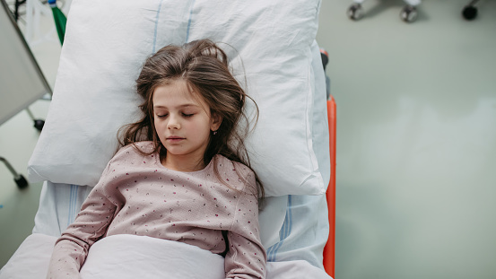 Little girl patient lying in hospital bed. Children in intensive care unit in hospital sleeping. Banner with copy space.