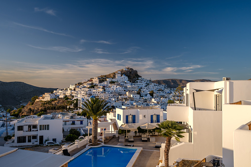 Ios, Greece - September 14, 2023 : View of a picturesque hotel with swimming pool and the whitewashed village of Ios Greece in the background