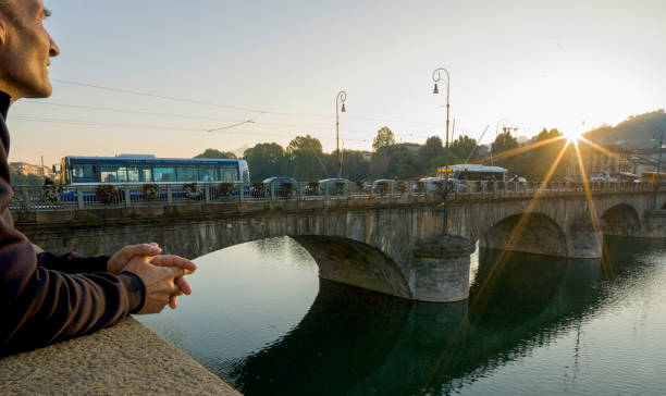 Businessman watches sunrise from bridge