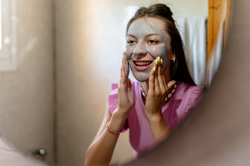 Within the confines of her bathroom, the young woman embarks on a self-care ritual, starting with a nourishing face mask