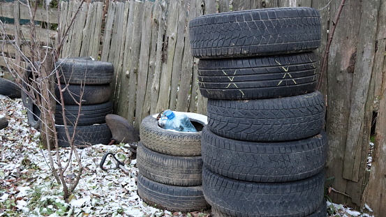 old car tires stand near an old wooden fence