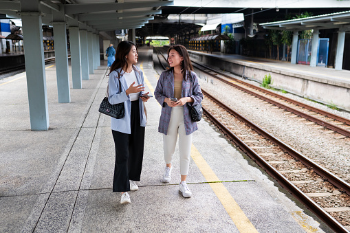 Two female Asian business travelers waiting for the train to go for work at Kuala Lumpur Railway Station in the morning.