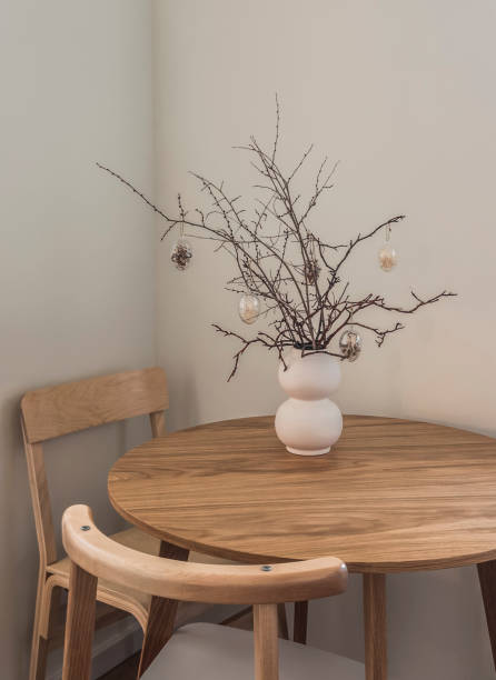 istock Minimalism Easter kitchen interior - round wooden table, chairs and Easter bouquet in a ceramic vase on the table 1929564225