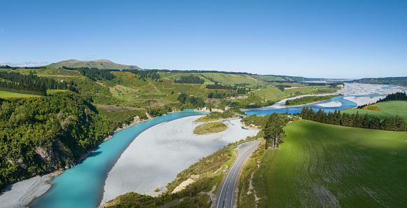 Experience the breathtaking allure of a winding glacier river amid lush green landscapes in New Zealand. Nature's masterpiece unfolds.