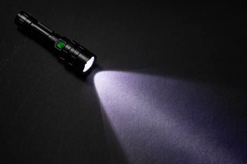 Flashlight and beam of light on a dark background,