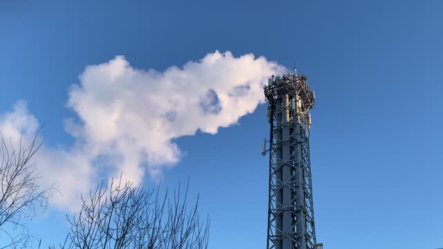 Smoke from a chimney against the blue sky on a frosty day