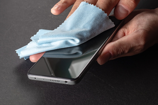 Germs elimination. Cleaning the smartphone screen with a fiber cloth from dirt dust and other external factors. Mobile Care Concept