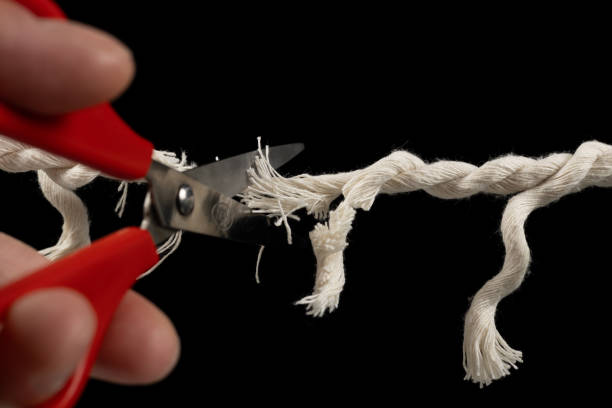 istock Worn rope ready to break, with scissors on black background. 1929573637