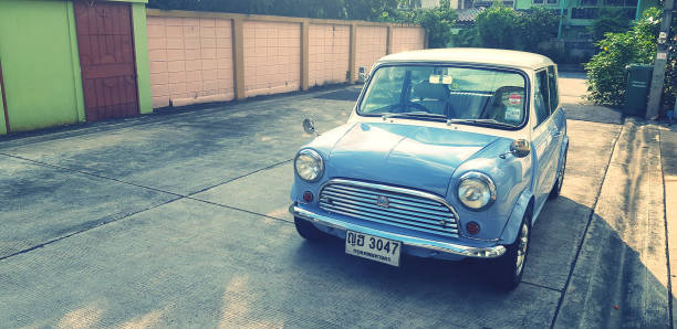Bangkok, Thailand- September 29, 2023: Blue and White classic Mini cooper car parked on street with sunlight and copy space in vintage color style. Transportation, Vintage and Retro vehicle concept.