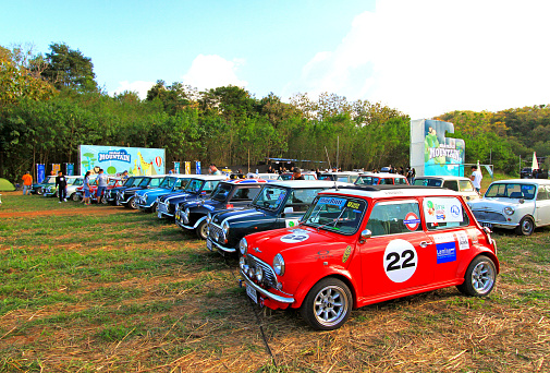 Nakhon Ratchasima, Thailand - December 6, 2023: Many old Classic Mini Austin cooper parked on grass field with green tree and blue sky background at Bonanza Khao Yai, Nakhon Ratchasima, Thailand.