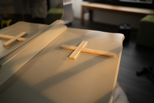 Sunlight from the window falls on the religious cross on the table in living room