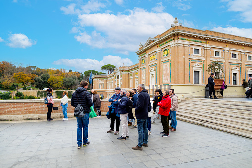 Rome, Italy. Vatican City. Groups of visitors to the Vatican Museums in the Cortile della Pigna (Courtyard of the Pinacoteca). Art Gallery building on the background. 2024-01-03.