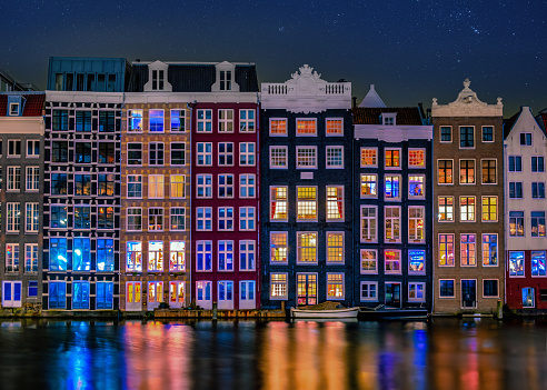 Amsterdam at night with dancing colorful houses at the Amsterdam canals in the Netherlands. colorful houses architecture in Amsterdam at night with colorful street lights and reflections in the canal