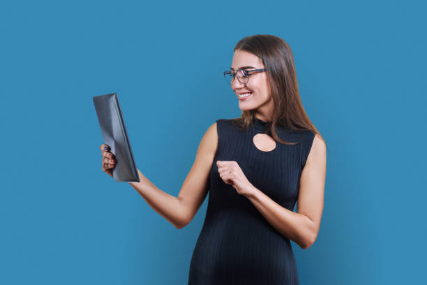 istock Young business woman with digital tablet on blue studio background 1929655471