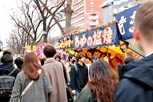 Tokyo, Japan-January 4, 2023:\nTakeshita Street in Harajuku is a one of the most popular streets in Tokyo especially among young people. The photo shows very crowded Takeshita Street during the New Year season. The street starts at one of the exits of  JR Harajuku Station. The street is flanked by various shops such as restaurants, coffee shops, souvenir shops etc.\nDue to the continued COVID-19 pandemic, most of Japanese visitors wear protective face mask.