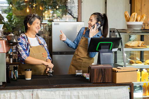 Two baristas female 60s senior mother and daughter happy making decision open cafe coffee shop small business startup after retirement, family relationship in eatery business working bonding together