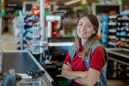 Portrate os smiling female cashier at the supermarket checkout