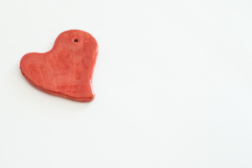 Red heart shaped ceramic piece with white background. No people