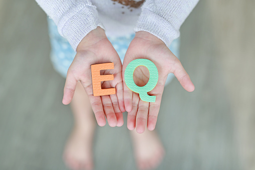 EQ (Emotional Quotient) sponge text on child hands. Education and development concept.