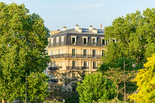 This landscape photo was taken, in Europe, in France, in ile de France, in Paris, in summer. We see a Haussmann Building, under the Sun.