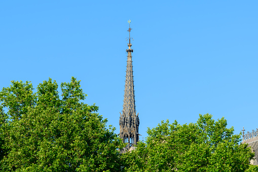 This landscape photo was taken, in Europe, in France, in ile de France, in Paris, on the banks of the Seine, in summer. We see the bell tower of the Sainte Chapelle on the Ile de la Cité, under the Sun.