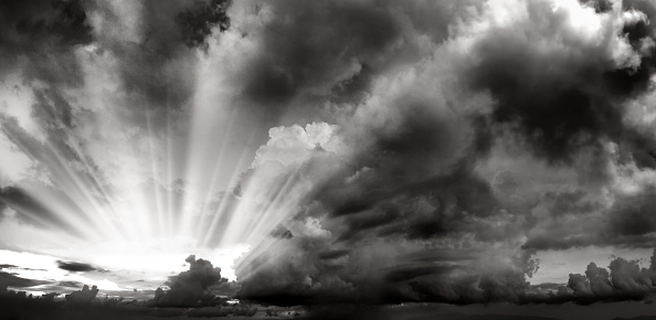 Black and white dramatic cloudy sky with shinning sun