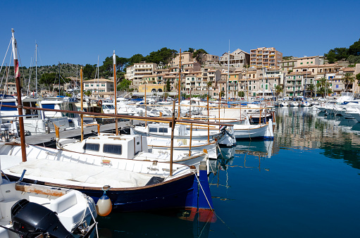 An image of Port de Soller in Majorca. The town is famous for its tram and picturesque harbour, with its array of boats and yachts set against a backdrop of rolling hills and the clear Mediterranean waters. This charming coastal town is also known for its scenic beauty and tranquil atmosphere, embodying the allure of the Balearic Islands.