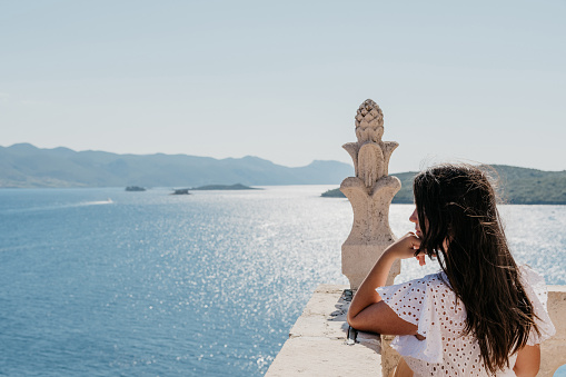 Young female standing on a tower deck overlooking the sea in Korcula town, Croatia