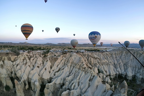 Cappadocia, Turkey - September 14, 2021: Drone shot of many hot air balloon flying over idyllic Love Valley in natural park, landmark or landscape of Goreme with fairy chimney