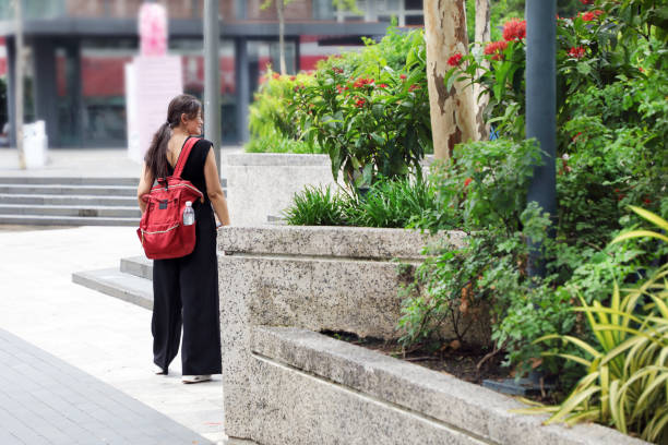 istock Cute Asian woman with backpack resting in city square 1929828439