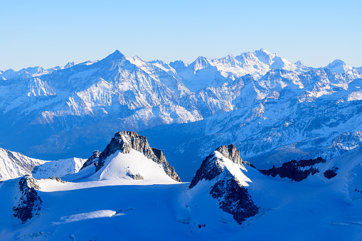 This landscape photo was taken in Europe, in France, Rhone Alpes, in Savoie, in the Alps, in winter. We see Mount Grivola and the Gran Paradiso covered in snow, under the Sun.