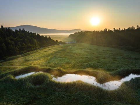 Aerial view of river flowing in the countryside at sunrise.