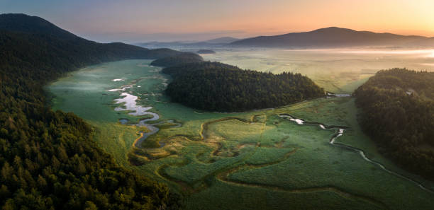 Winding River In Countryside Aerial view of river flowing in the countryside at sunrise. cerknica lake stock pictures, royalty-free photos & images