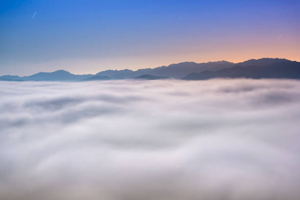 The sea of clouds on a quiet moonlit night makes you feel unpredictable. Peaks surrounding Emerald Reservoir. Xindian District, New Taipei City, Taiwan.