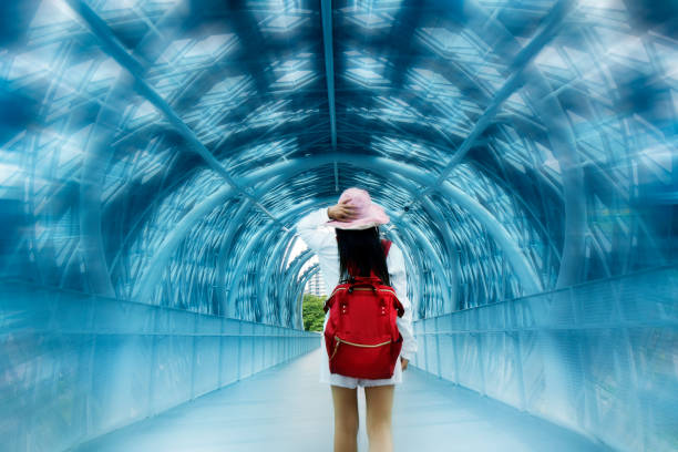 istock Young woman with backpack walking in pedestrian walkway tunnel 1929861762