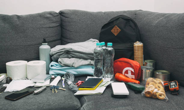 istock Emergency backpack equipment organized on the table. Documents, water,food, first aid kit and another items needed to survive. 1929871510