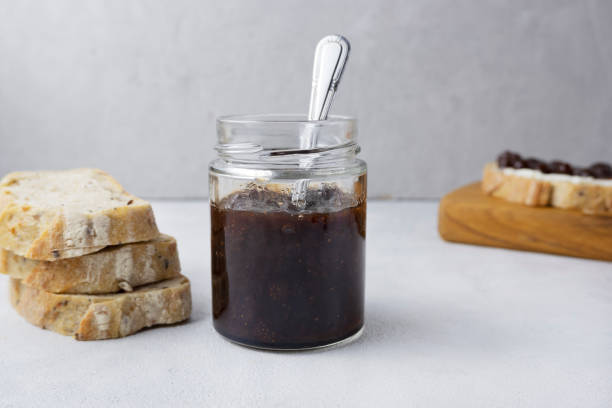 istock Strawberry jam in a glass jar on a light gray background with sliced bread. Composition with delicious homemade jam. Breakfast and snack concept. 1929874360