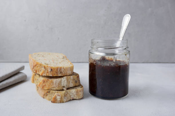 istock Strawberry jam in a glass jar on a light gray background with sliced bread. Composition with delicious homemade jam. Breakfast and snack concept. 1929874931