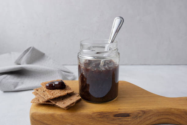 istock Strawberry jam in a glass jar on a light gray background with sliced bread. Composition with delicious homemade jam. Breakfast and snack concept. 1929874934