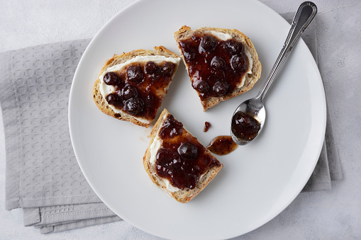 Whole grain bread with strawberry jam on top. Composition with delicious homemade jam on a plate. Breakfast and snack concept.