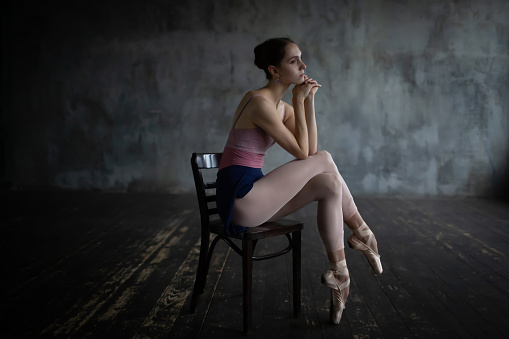 Tired ballerina sits on a chair.