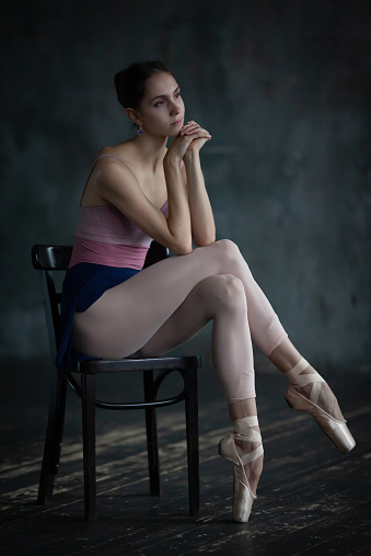 Portrait of a beautiful young ballerina sitting on a chair.